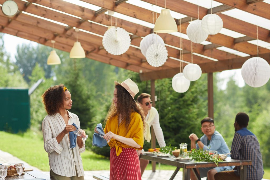 Friends under a pergola preparing for summer party.