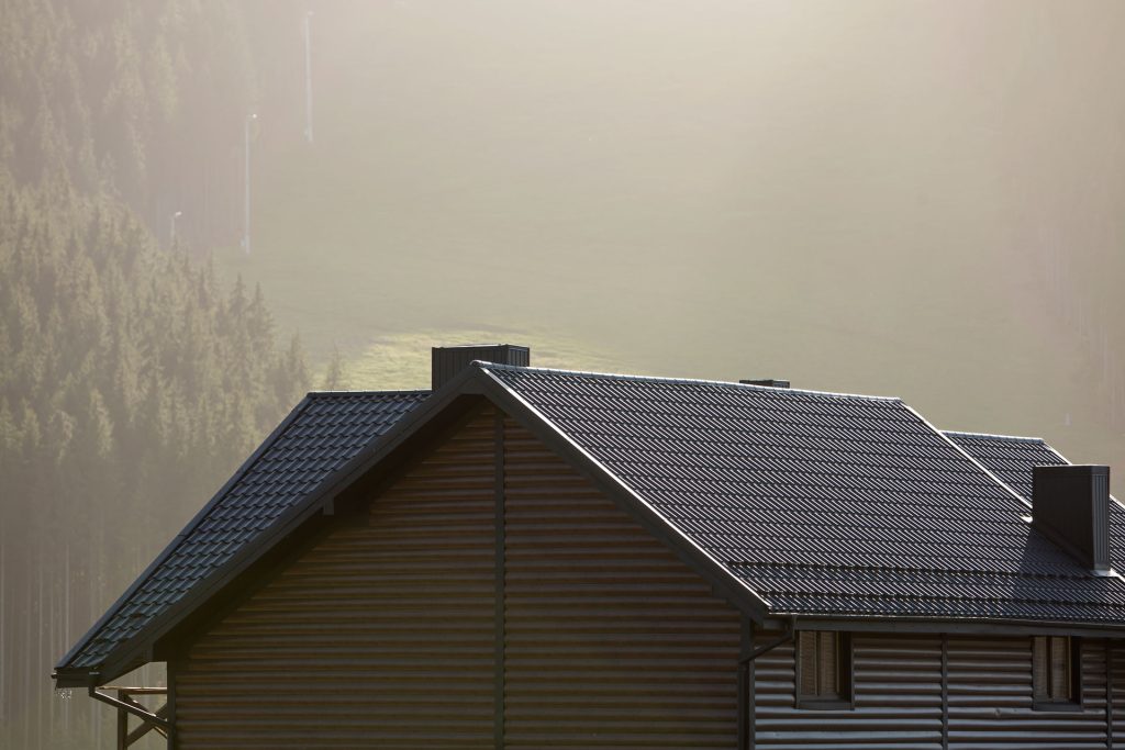Roof of a cottage with brown siding and shingle roofing, showcasing maintenance and durability essential for protecting home value and structure in Redding's climate.