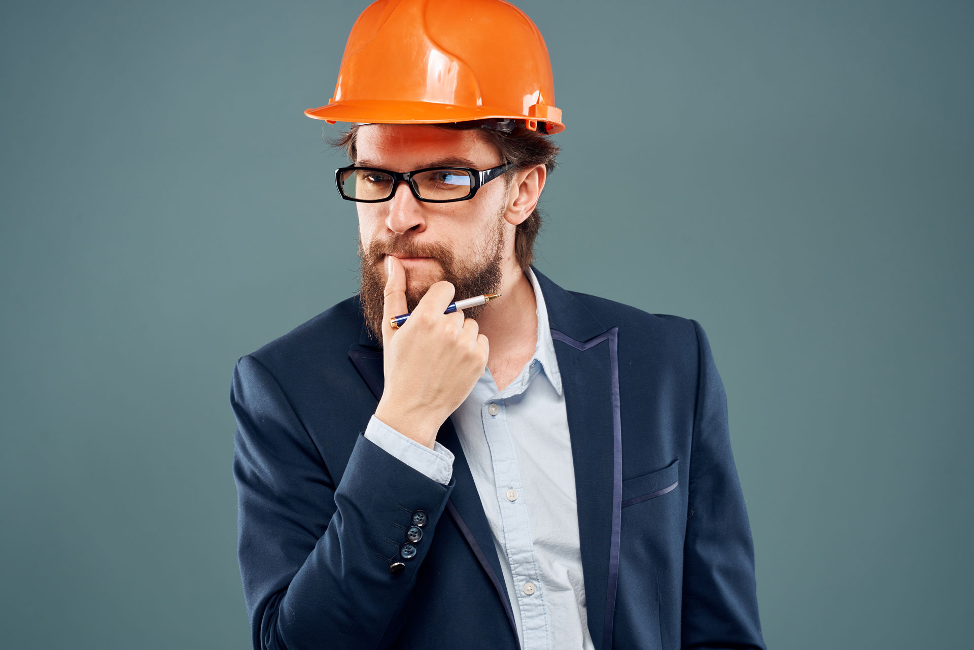 A man in suit with orange hard hat thinking.
