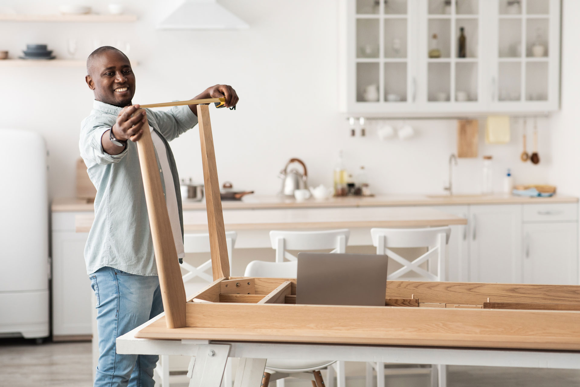 African American man measuring the width of the table feet.