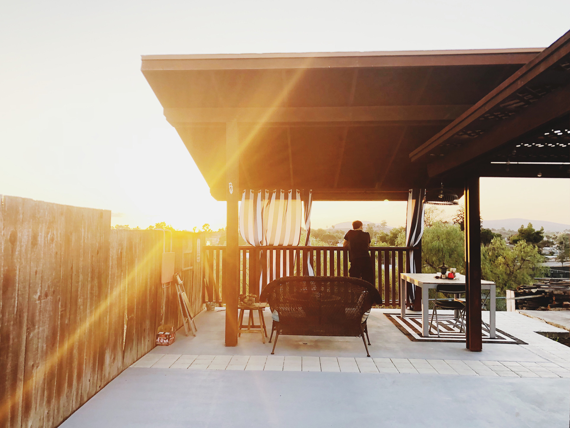 Person enjoying sunset under covered deck.